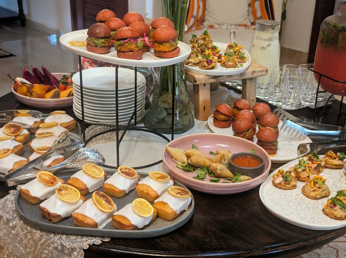 Tiered platters of pink slider buns, iced lemon loaves, samosas and small bites