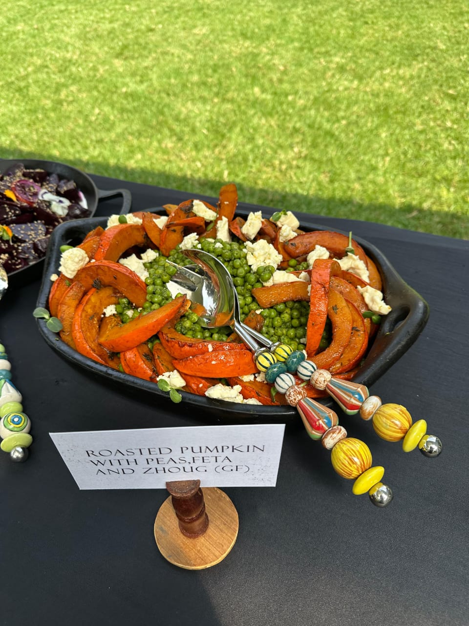 Roasted pumpkin with peas, feta and zhoug on a shared platter at a garden event